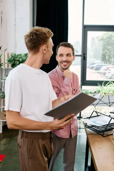 Two stylish men engage in a lighthearted conversation while working together. — Stock Photo