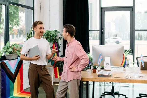 In einem lebhaften Büro führt ein fröhliches Paar lebhafte Gespräche, umgeben von stolzen Fahnen. — Stockfoto