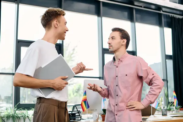 A handsome gay couple discusses ideas enthusiastically in a stylish workspace with bright light. — Stock Photo