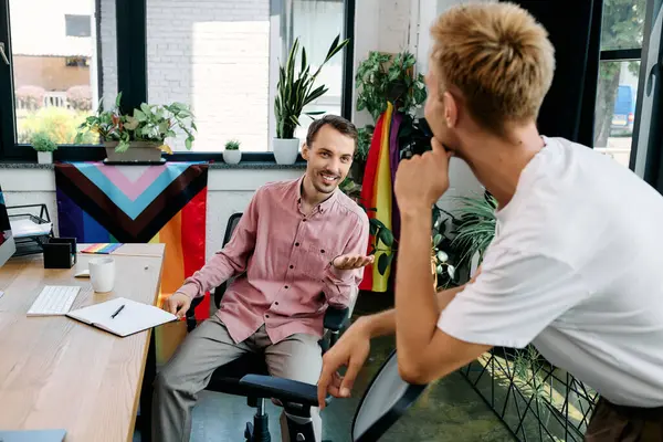 Two men engage in a warm and playful discussion while surrounded by plants and vibrant decor. — Stock Photo