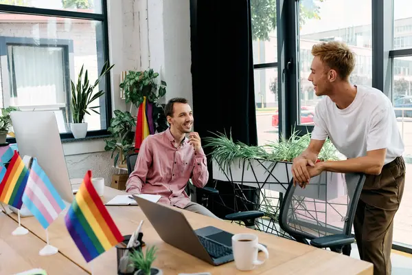 A handsome couple engages in a light hearted conversation in a colorful workspace. — Stock Photo