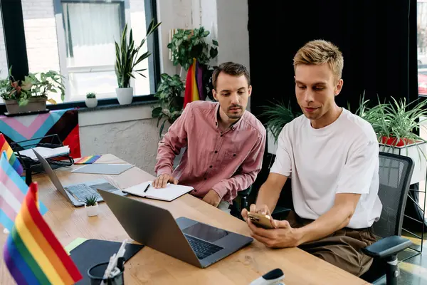 A handsome couple collaborates enthusiastically in a vibrant office adorned with pride flags. — Stock Photo
