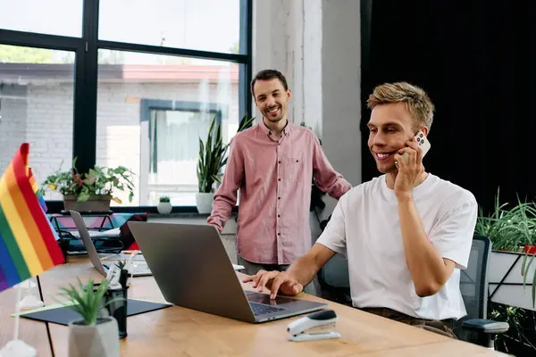 A cheerful young man talks on the phone while his partner smiles, creating a productive atmosphere. — Stock Photo
