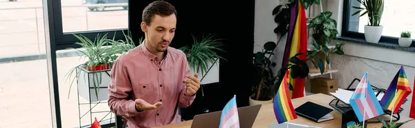 Attractive man working in office surrounded by colorful pride flags. — Stock Photo