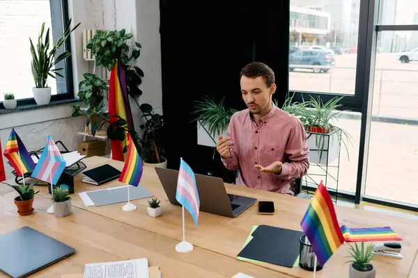 Handsome man working in office surrounded by colorful pride flags. — Stock Photo
