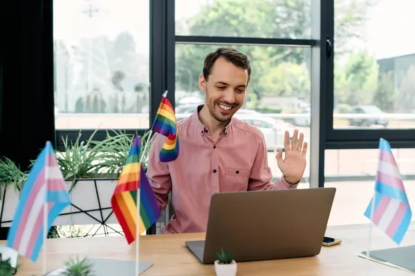 Joyous man working in office surrounded by colorful pride flags. — Stock Photo