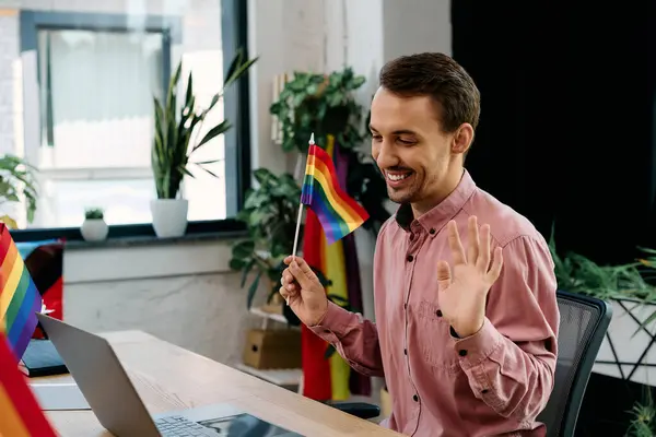 Cheerful man working in office surrounded by colorful pride flags. — Stock Photo