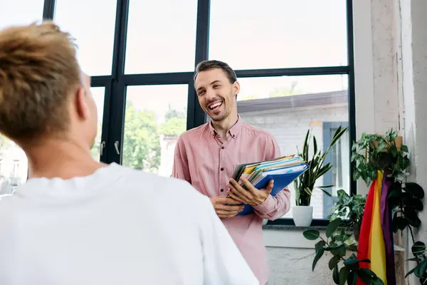 A joyful interaction between two men in a cheerful office filled with greenery and natural light. — Stock Photo