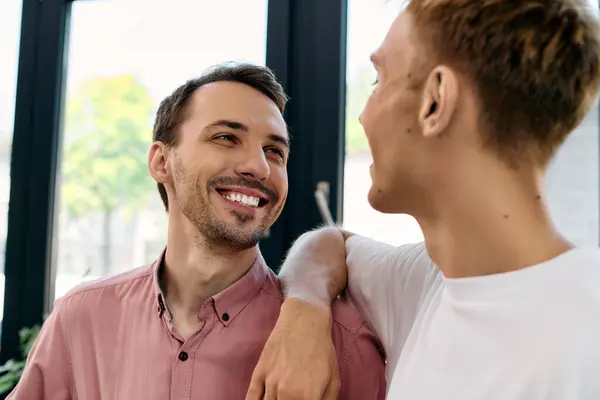 Two handsome men share smiles and laughter while enjoying their time in a sunny office. — Stock Photo