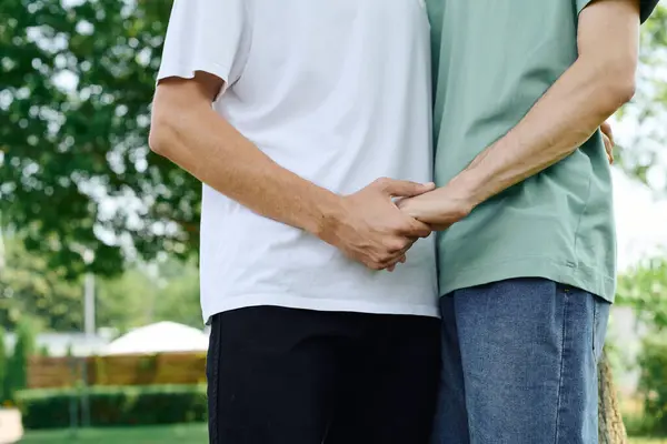 A loving gay couple embraces deeply in a lush green park, celebrating their connection. — Stock Photo