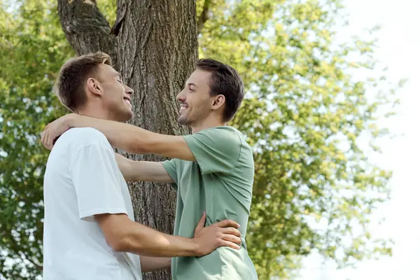 A loving couple embraces warmly, basking in the beauty of a serene, vibrant park. — Stock Photo