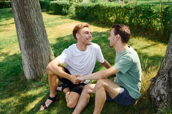 A cheerful couple share smiles while sitting on the grass, enjoying their time together in nature. — Stock Photo