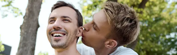 Ein fröhliches Paar genießt die Gesellschaft des anderen, während es sich in einem sonnigen Park zärtlich küsst. — Stockfoto