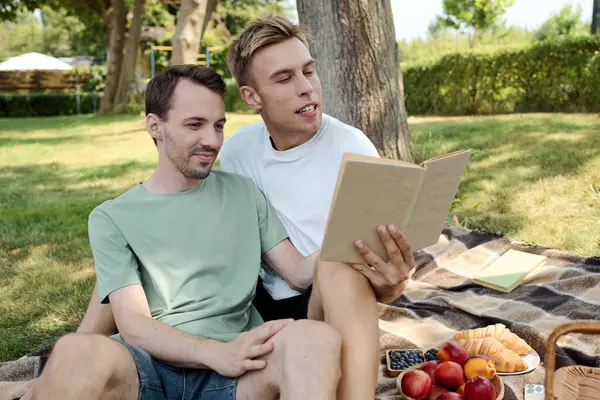 A charming couple relaxes on a picnic blanket, sharing a book and enjoying the beautiful outdoors. — Stock Photo