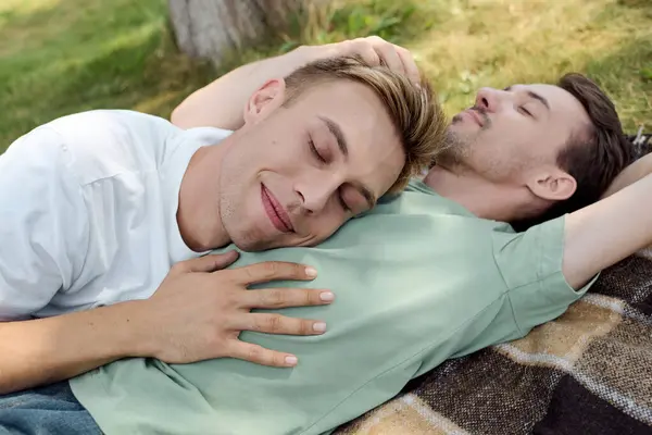 Two joyful partners share a tender moment while lounging on a blanket in a beautiful park. — Stock Photo