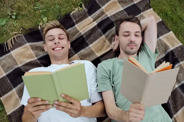 Two men relax on a blanket, deeply engaged in their books while enjoying natures tranquility. — Stock Photo