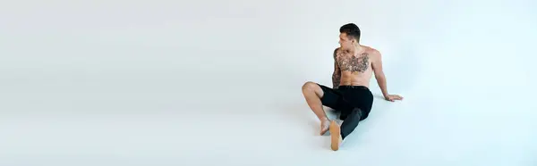 Um jovem tatuado relaxa em um estúdio, exibindo orgulhosamente sua perna protética e espírito artístico. — Fotografia de Stock