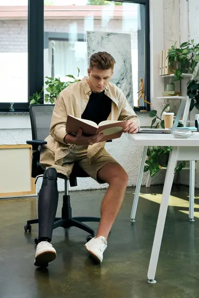 A young man focused on an engaging book while seated in a stylish office filled with plants and natural light. — Stock Photo