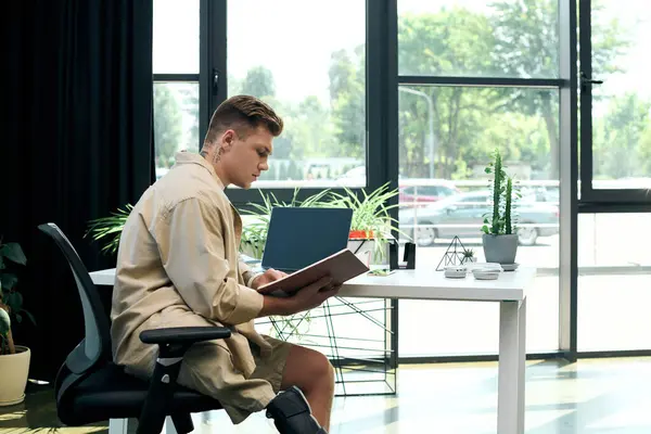 A young man with a prosthetic leg focuses intently on his work in a contemporary office environment. — Stock Photo