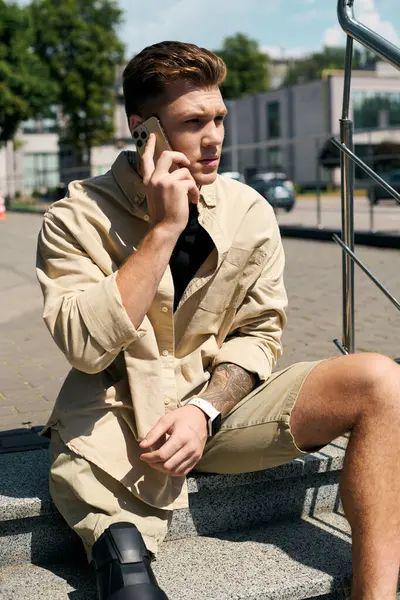 A young man with a prosthetic leg is engaged in a phone conversation outside a contemporary office building. — Stock Photo