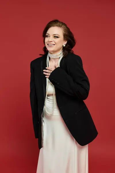 A young woman is playfully smiling while wearing a formal outfit and pearls. — Stock Photo