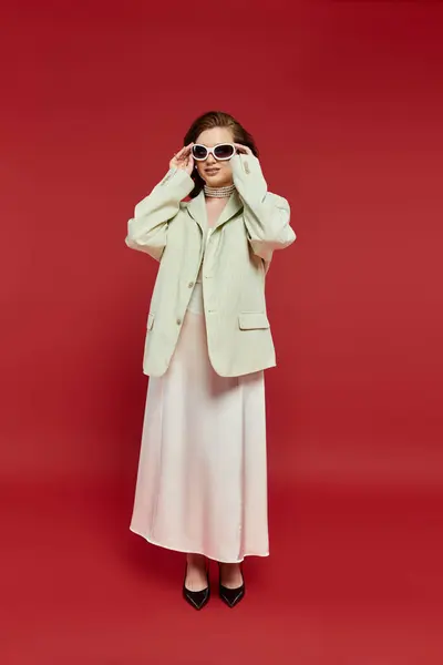 Eine modische Frau steht selbstbewusst da und präsentiert ihre elegante Kleidung und trendige Sonnenbrille. — Stockfoto
