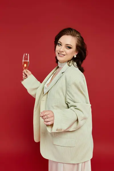 A young woman in stylish attire joyfully toasts with a sparkling drink. — Stock Photo