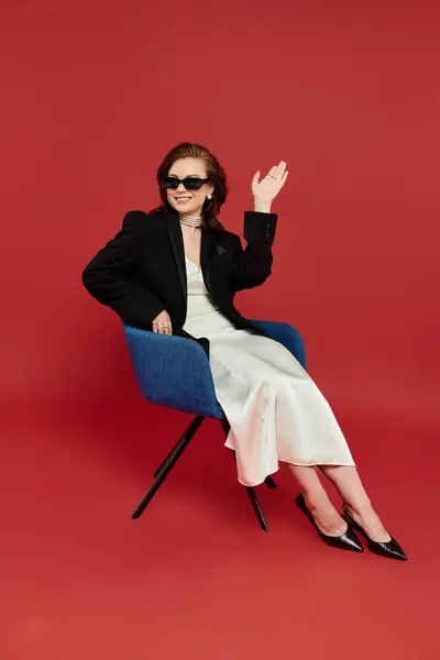 A young beautiful woman dressed elegantly sits gracefully, exuding confidence in style. — Stock Photo