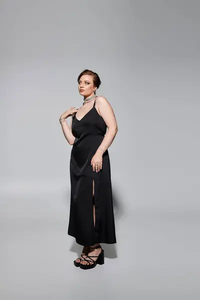 A young woman showcases her elegant style in a sophisticated black dress and striking accessories. — Stock Photo