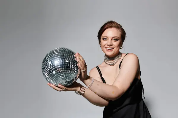 A young woman in elegant clothes beams while holding a shiny disco ball, embracing the vibe. — Stock Photo