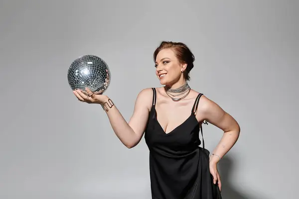 A graceful young woman radiates confidence as she holds a sparkling disco ball. — Stock Photo