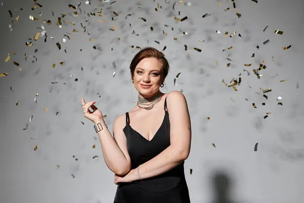 A young woman in elegant attire stands confidently as confetti swirls around her. — Stock Photo