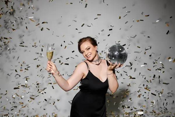 A beautifully dressed woman holds a drink and disco ball, enjoying a lively celebration. — Stock Photo