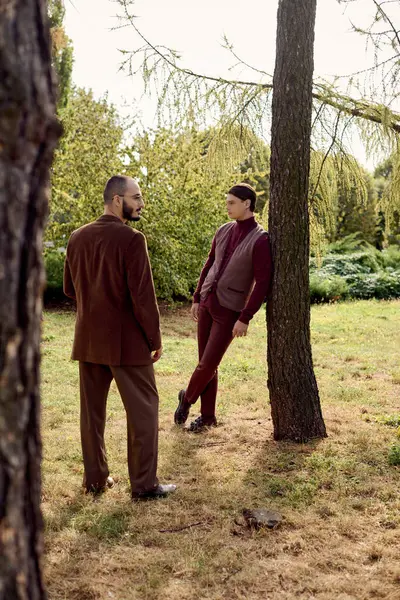 Two fashionable men share a moment in a picturesque autumn field, appreciating the seasonal charm. — Stock Photo