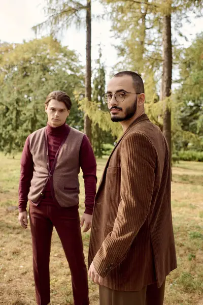 Two handsome men showcase their fashionable autumn attire in a picturesque field surrounded by nature. — Stock Photo