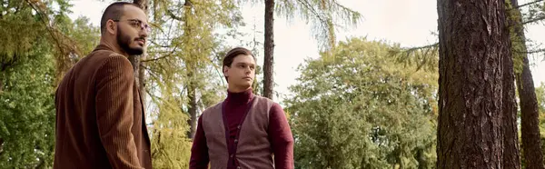 Two men dressed in fashionable autumn outfits soak in the beauty of a colorful field during fall. — Stock Photo