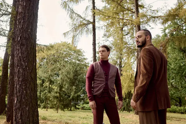 Two well-dressed men pose thoughtfully in a scenic autumn landscape, surrounded by colorful foliage. — Stock Photo