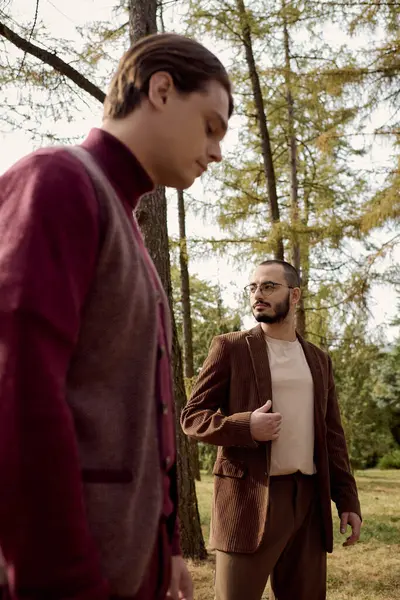 Handsome men showcase fashionable autumn outfits while embracing the beauty of nature in a vibrant field. — Stock Photo