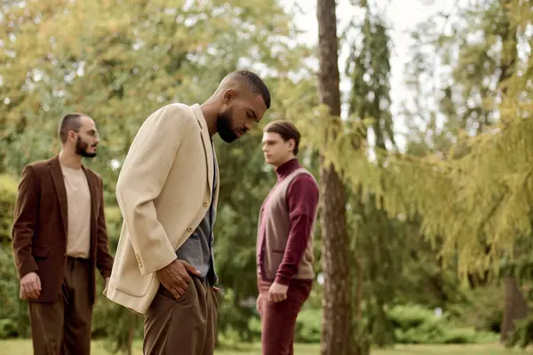 Three men exude charm and elegance while posing in a stunning autumn field filled with colorful foliage. — Stock Photo