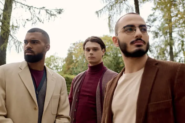 Trois hommes à la mode présentent leur tenue d'automne tout en profitant d'un moment tranquille dans la nature. — Photo de stock