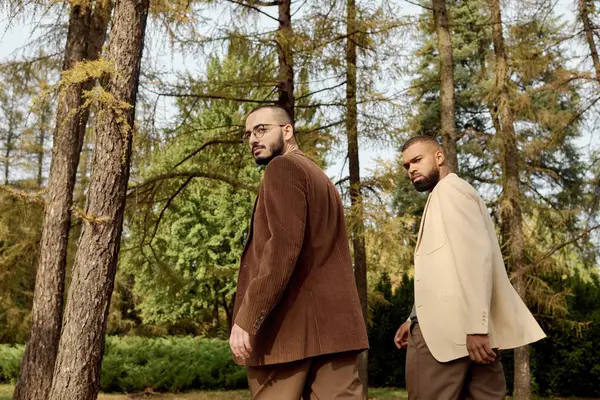 Two fashionable men enjoy a serene moment in an autumn field, showcasing their stylish outfits amid nature. — Stock Photo