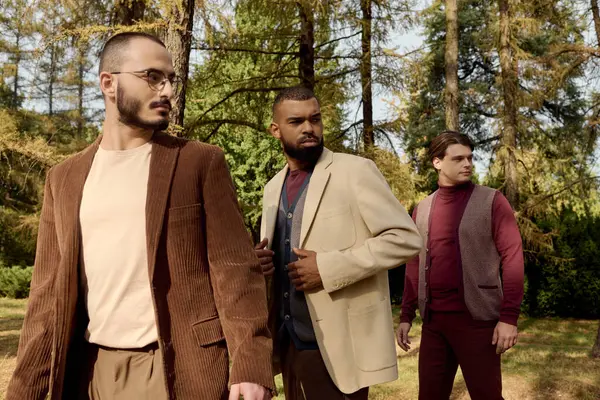 Three handsome men showcase their fashionable autumn outfits in a picturesque natural setting. — Stock Photo