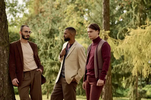 Three handsome men pose confidently in a picturesque autumn field, exuding charm and style. — Stock Photo