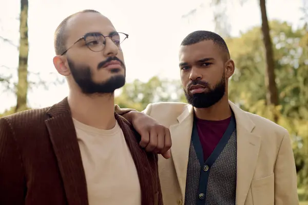 Two fashionable men showcase their autumn styles, enjoying a peaceful moment in a colorful field. — Stock Photo