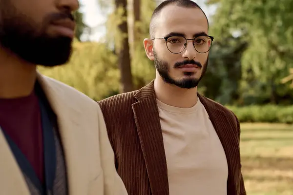 Two handsome men showcase their fashionable autumn outfits amidst a tranquil natural setting. — Stock Photo