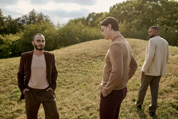Three handsome men showcase autumn fashion while enjoying a serene moment in a vibrant natural setting. — Stock Photo