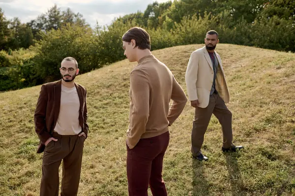 Handsome men flaunt trendy autumn outfits while posing together in a serene field setting. — Stock Photo