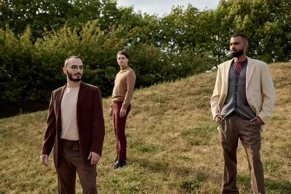Three fashionable men stand confidently in an autumn field, showcasing their stylish outfits amidst nature. — Stock Photo