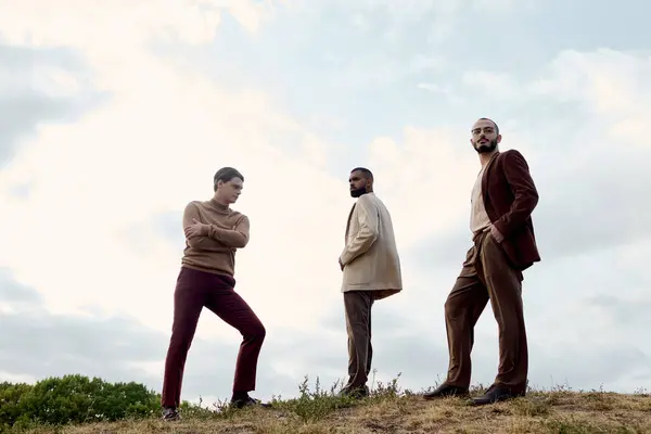 Three handsome men showcase fashionable autumn attire while standing in a picturesque field during fall. — Stock Photo