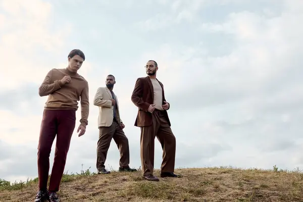 Three handsome men showcase stylish autumn outfits while enjoying nature in a tranquil field setting. — Stock Photo